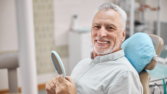 smiling older man after receiving his implant restorations